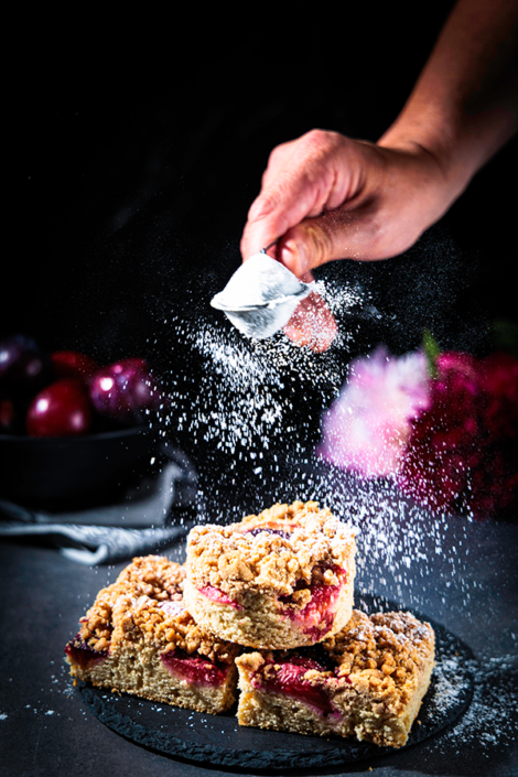 Food Fotografie und Food Styling von Streuselkuchen mit Pflaumen in Aktion von vorne aufgenommen